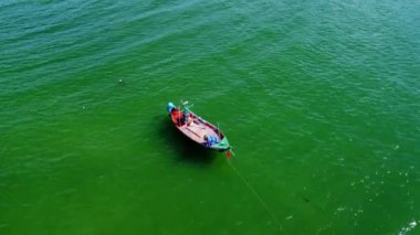 Tayland 'ın güneyindeki küçük bir balıkçı limanına demirlenmiş geleneksel renkli Tayland ahşap balıkçı teknelerinin insansız hava aracı görüntüsü. Denizde bir sürü uzun kuyruklu tekne var.