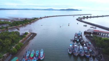 Tayland 'ın güneyindeki küçük bir balıkçı limanına demirlenmiş geleneksel renkli Tayland ahşap balıkçı teknelerinin insansız hava aracı görüntüsü. Denizde bir sürü uzun kuyruklu tekne var.