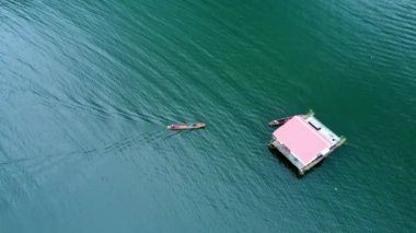 Kwai Nehri 'nin havadan görünüşü ve Kanchanaburi Eyaleti, Tayland' da yüzen evler. Yüzen kulübelerin ve Kwai Nehri üzerinde yüzen Tayland uzun kuyruklu teknelerinin güzel manzarası..