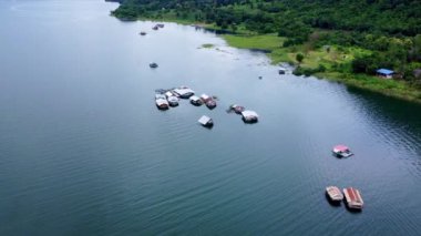 Kwai Nehri 'nin havadan görünüşü ve Kanchanaburi Eyaleti, Tayland' da yüzen evler. Yüzen kulübelerin ve Kwai Nehri üzerinde yüzen Tayland uzun kuyruklu teknelerinin güzel manzarası..