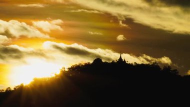 Dramatik dağ siluetleri üzerinde gün batımı manzarası altın gökyüzü ve arka planda bulutlar.