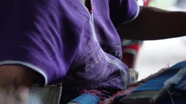 Yaşlı Karen kadın geleneksel dokuma tezgahıyla dokuyor doğal boyalarla boyanmış iplikten renkli desenler yaratıyor..