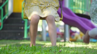 Şirin kız kardeşler parkta salıncakta sallanırken eğleniyorlar. Yaz tatili boyunca oyun bahçesinde oynayan çocuklar.