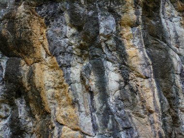 Volkanik kayanın sıkıştırılmış kaya yapısı ile inanılmaz bir yamaç. Volkanik kayanın yakın çekim dokusu. Kırık kırık parçalanmış.