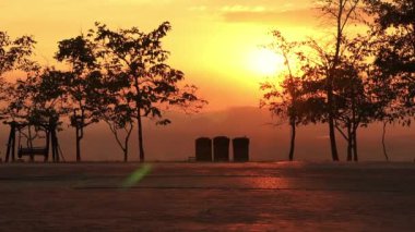 Parkta gün batımında parkta scooter süren şirin kız kardeşlerin silueti. Çocuk için aktif eğlence ve açık hava sporu.