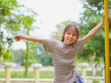 Parktaki parkta salıncakta sallanan tatlı kız eğleniyor. Yaz tatili boyunca oyun bahçesinde oynayan çocuklar.