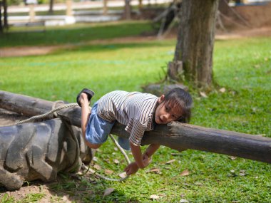 Açık hava parkında denge kirişinde yürüyen tatlı küçük kız. Yaz tatili boyunca oyun bahçesinde oynayan çocuklar.