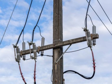 Parlak gökyüzü arka planında elektrik kabloları olan elektrik direği.