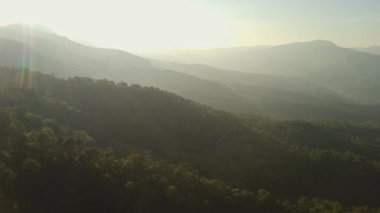 Kış dağlarında güzel bir günbatımı. Batan güneş, akşamları tropikal ağaçlarla kaplı sakin bir dağ manzarasında parlıyor..