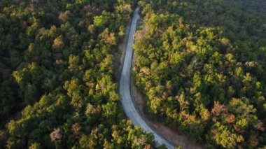Akşamları yeşil orman ve dağdan geçen kırsal bir yolun havadan görüntüsü..