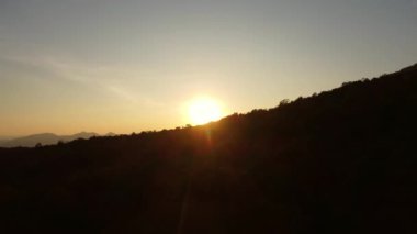 Kış dağlarında güzel bir günbatımı. Batan güneş, akşamları tropikal ağaçlarla kaplı sakin bir dağ manzarasında parlıyor..