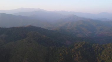 Kışın dağda güzel bir gün doğumu. Güneş, sabahın erken saatlerinde tropikal ağaçlarla kaplı sakin bir dağ manzarasında parlıyor..