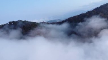 Görünür siluetleri olan dağ siluetleri rengarenk sislerin içinden sabah görülebiliyor. Sis denizinin ortasında görkemli dağlar.