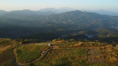 Kırsal yolda, akşamları tropikal orman ve dağlardan geçen arabanın hava görüntüsü..