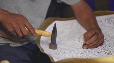 Sanatçının eli, atölyedeki aletleri ve karmaşık teknikleri kullanarak geleneksel gölge kuklaları ustalıkla hazırlıyor..