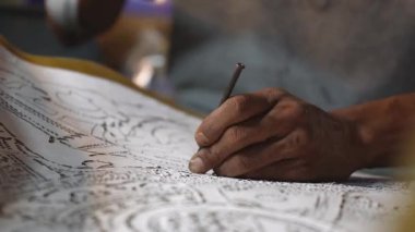 Sanatçının eli, atölyedeki aletleri ve karmaşık teknikleri kullanarak geleneksel gölge kuklaları ustalıkla hazırlıyor..