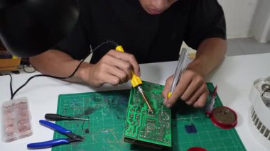 Asyalı erkekler evdeki elektronik cihazları veya elektrikli aletleri tamir ediyorlar..