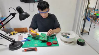 Asyalı erkekler evdeki elektronik cihazları veya elektrikli aletleri tamir ediyorlar..