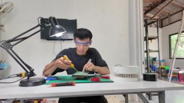 Asyalı erkekler evdeki elektronik cihazları veya elektrikli aletleri tamir ediyorlar..