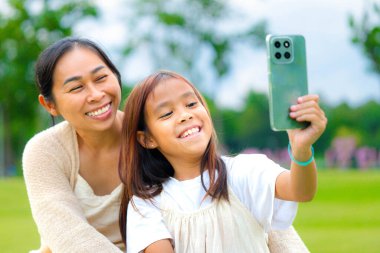 Mutlu anne ve kız baharda bir parkta birlikte vakit geçiriyorlar..