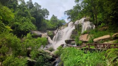 Yağmur mevsiminde güçlü bir şekilde akan ormandaki şelalenin doğası. Nehirdeki güçlü akıntı, sonbaharda sağanak yağışlardan sonra sular çamurlu oldu..
