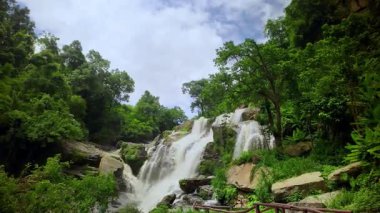 Yağmur mevsiminde güçlü bir şekilde akan ormandaki şelalenin doğası. Nehirdeki güçlü akıntı, sonbaharda sağanak yağışlardan sonra sular çamurlu oldu..