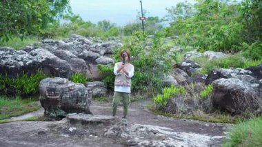 Küçük mutlu bir turist, ulusal bir parkta dağ manzarası arasında video kaydetmek için bir video kamera kullanıyor..