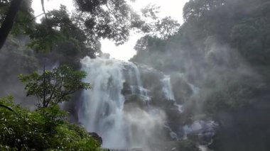 Yağmur mevsiminde güçlü bir şekilde akan ormandaki şelalenin doğası. Nehirdeki güçlü akıntı, sonbaharda sağanak yağışlardan sonra sular çamurlu oldu..