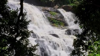Yağmur mevsiminde güçlü bir şekilde akan ormandaki şelalenin doğası. Nehirdeki güçlü akıntı, sonbaharda sağanak yağışlardan sonra sular çamurlu oldu..