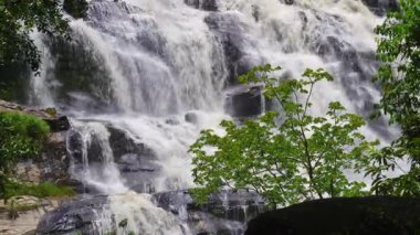 Yağmur mevsiminde güçlü bir şekilde akan ormandaki şelalenin doğası. Nehirdeki güçlü akıntı, sonbaharda sağanak yağışlardan sonra sular çamurlu oldu..