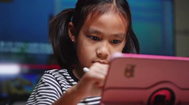 Elektronik tablet ve stil kalem kullanan sevimli Asyalı kız çizimi. Dijital tablet kullanan Asyalı ilkokul öğrencisi evde oturma odasında oturuyor..