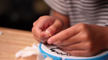 Bir kızın elinin yakın plan bir çerçeve ile bir nakış çemberi işlemesi. El yapımı bir kız tuvale dikiş deseni.