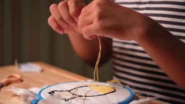 Bir kızın elinin yakın plan bir çerçeve ile bir nakış çemberi işlemesi. El yapımı bir kız tuvale dikiş deseni.