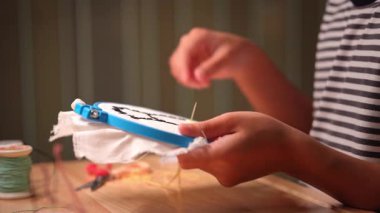 Bir kızın elinin yakın plan bir çerçeve ile bir nakış çemberi işlemesi. El yapımı bir kız tuvale dikiş deseni.