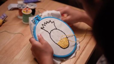 Bir kızın elinin yakın plan bir çerçeve ile bir nakış çemberi işlemesi. El yapımı bir kız tuvale dikiş deseni.