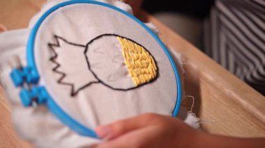 Bir kızın elinin yakın plan bir çerçeve ile bir nakış çemberi işlemesi. El yapımı bir kız tuvale dikiş deseni.