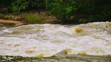 Yağmur mevsiminde güçlü bir şekilde akan ormandaki şelalenin doğası. Nehirdeki güçlü akıntı, sağanak yağmurdan sonra sular çamurlu oldu..