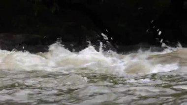 Yağmur mevsiminde güçlü bir şekilde akan ormandaki şelalenin doğası. Nehirdeki güçlü akıntı, sağanak yağmurdan sonra sular çamurlu oldu..
