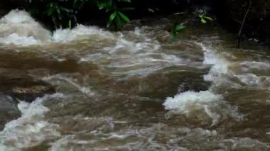 Yağmur mevsiminde güçlü bir şekilde akan ormandaki şelalenin doğası. Nehirdeki güçlü akıntı, sağanak yağmurdan sonra sular çamurlu oldu..
