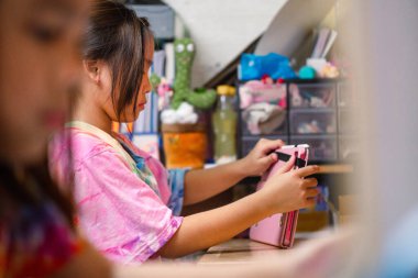 İki ilkokul kızı evdeki masalarında ders çalışıyor. İki tatlı kız öğrenci özenle ödevlerini yapıyor..