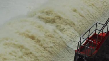 Nehrin aşağısındaki barajın güçlü akım ve kahverengi çamur akıntısıyla sel sularını serbest bırakması.