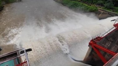 Nehrin aşağısındaki barajın güçlü akım ve kahverengi çamur akıntısıyla sel sularını serbest bırakması.