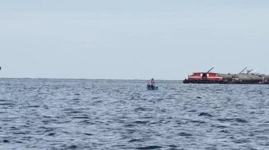 Denizcilik, lojistik ve küresel taşımayı sembolize eden açık denizde demirlemiş gemileri olan endüstriyel bir nakliye limanında büyük kargo vinçleri..