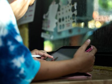 İnternette öğrenmek ve evde okumak için dijital tablet kullanan genç bir kız. İmaj modern eğitimi, çocukluktaki teknolojiyi ve öğrencilerin dijital yaşam tarzını temsil ediyor. E-öğrenim, evde eğitim ve c kavramlarını göstermek için mükemmel.