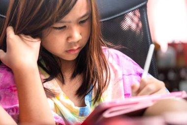 İnternette öğrenmek ve evde okumak için dijital tablet kullanan genç bir kız. İmaj modern eğitimi, çocukluktaki teknolojiyi ve öğrencilerin dijital yaşam tarzını temsil ediyor. Resim için mükemmel.