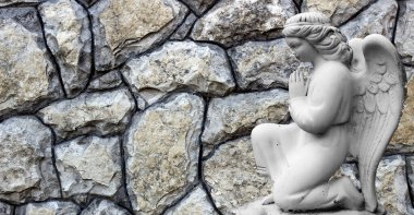 Arka planda dizlerinde kanatları olan küçük bir melek.