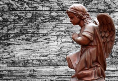 Arka planda dizlerinde kanatları olan küçük bir melek.