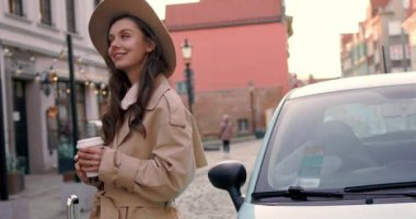 Şehir binalarında telefon kullanırken yürürken sevimli çekici bir kadın etrafına bakıyor güneş ışığında mutlu bir gülücük atıyor. Portre, genç, internet, cep telefonu, sokak, güzel, seyahat, mobil, şık. Yavaş