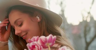 Şehir binalarında telefon kullanırken yürürken sevimli çekici bir kadın etrafına bakıyor güneş ışığında mutlu bir gülücük atıyor. Portre, genç, internet, cep telefonu, sokak, güzel, seyahat, mobil, şık. Yavaş