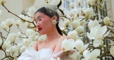 Asian woman enjoying nature, touching flowers in Garden with blooming magnolia.